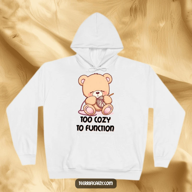 Funny sleepy teddy bear hoodie featuring a drowsy bear attempting to knit, symbolizing comfort, coziness, and hilarious crafting mishaps.