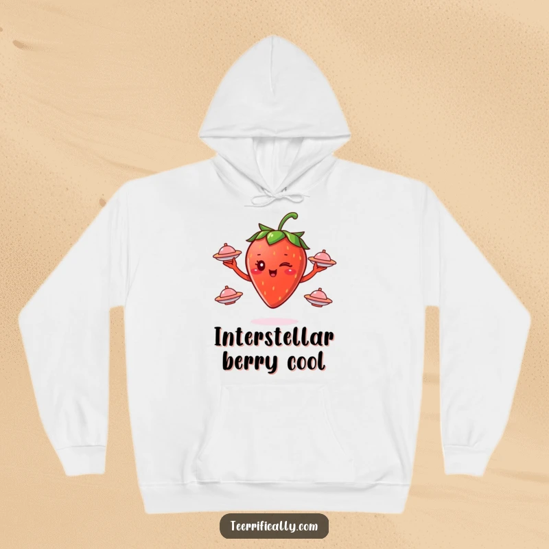 Funny winking strawberry juggling small flying saucers, depicted on a cozy hoodie, radiating cosmic, humorous, and warm vibes.