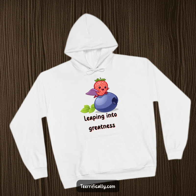 Funny strawberry superhero hoodie, a happy strawberry with a cape leaping over a blueberry, cozy and heroic.